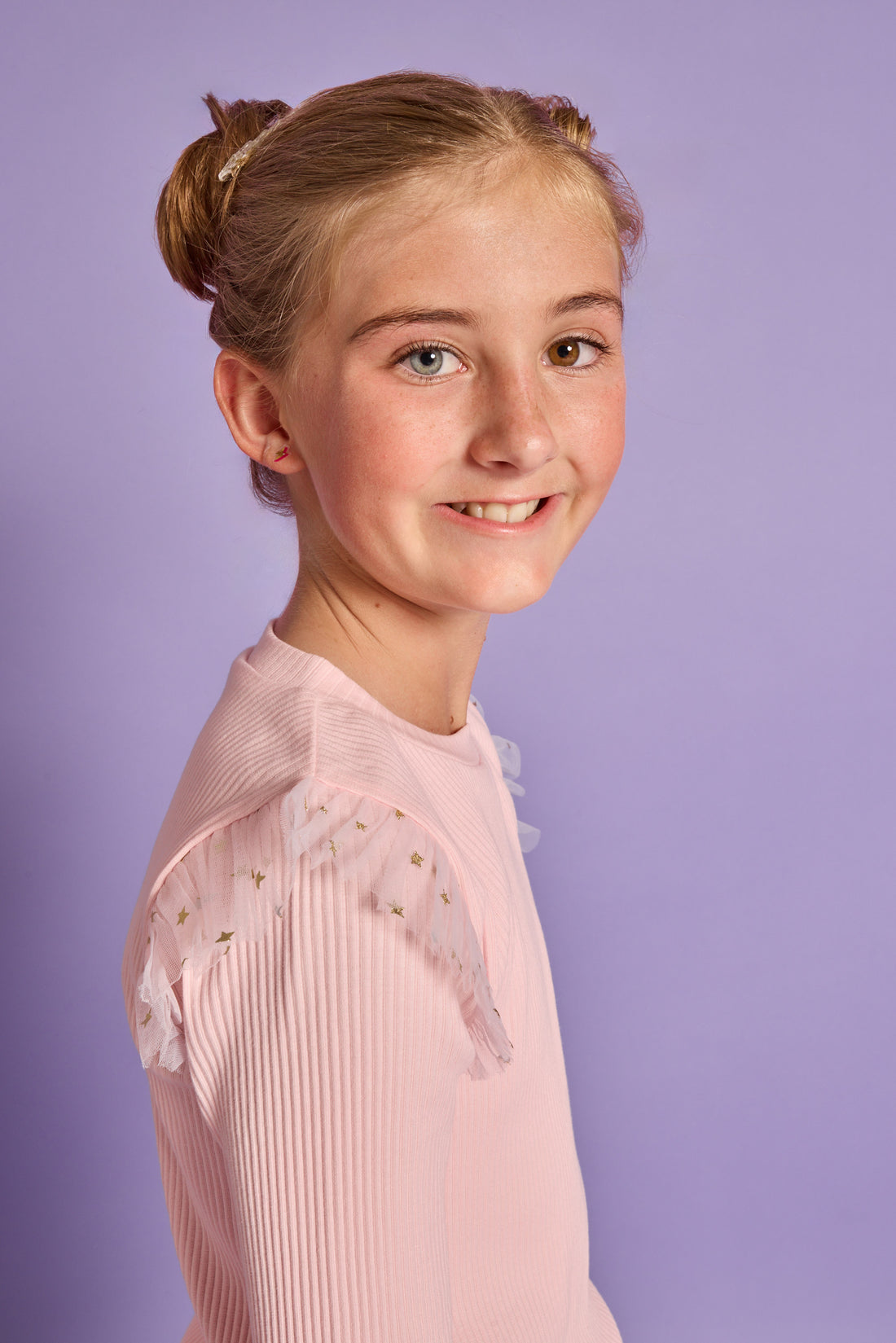 Model can be seen wearing a bubblegum pink ribbed knit long sleeve t-shirt with tulle sparkle star fabric at top of sleeves for elevated look.