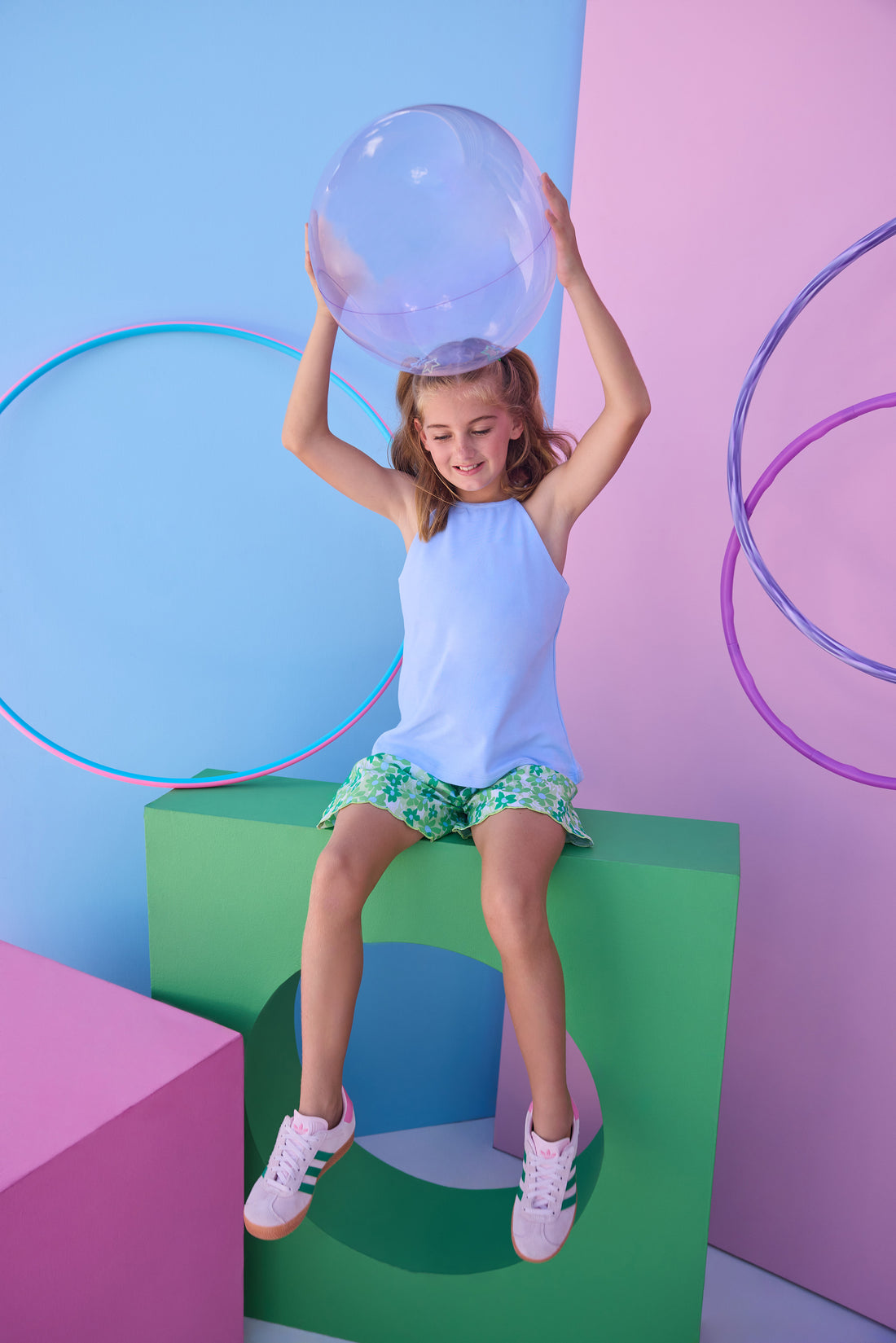 Tween model can be seen wearing a knit light blue halter tank top that features button closure along back and made of a soft comfy material. Top pairs back perfectly with woven shirred shorts in a beautiful green/light blue print to complete the look. 