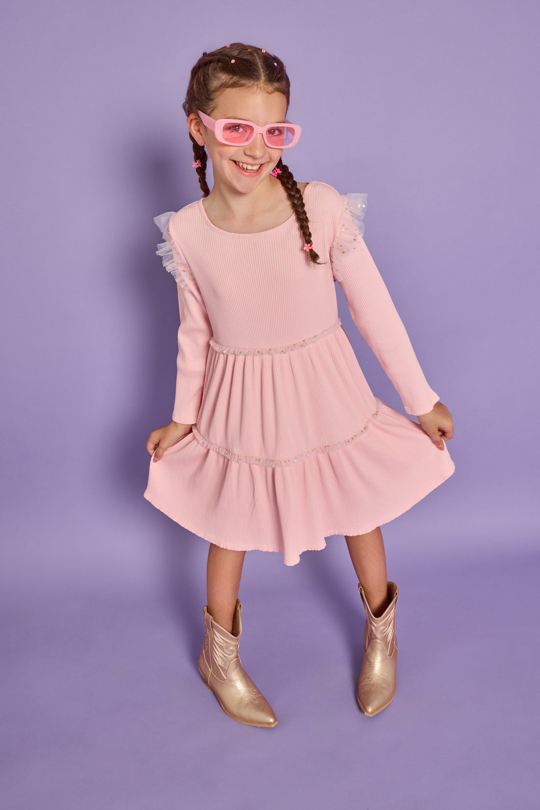 Model can be seen wearing soft knit ribbed pink dress that has sparkle star tulle along two tiers and the same tulle at sleeves for an angel sleeve effect. 