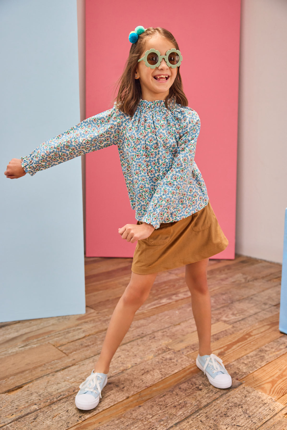 Model can be seen wearing brown/blue/green floral print woven shirt that features a high neck elastic collar which gives it the ruching affect. Top pairs back perfectly with brown faux suede skort to complete the look. 