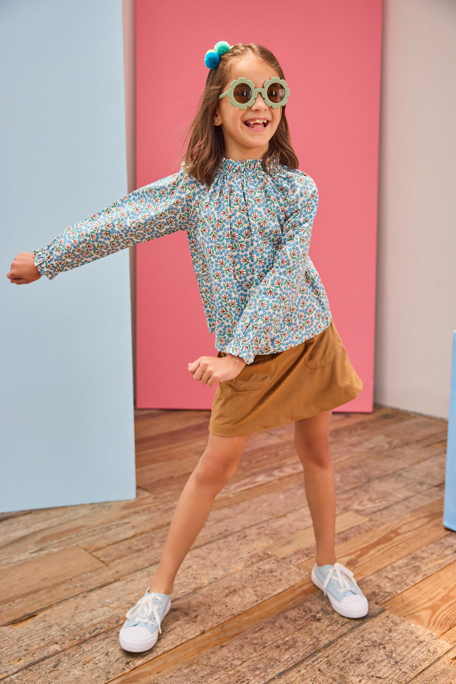 Model can be seen wearing brown/blue/green floral print woven shirt that features a high neck elastic collar which gives it the ruching affect. Top pairs back perfectly with brown faux suede skort to complete the look. 