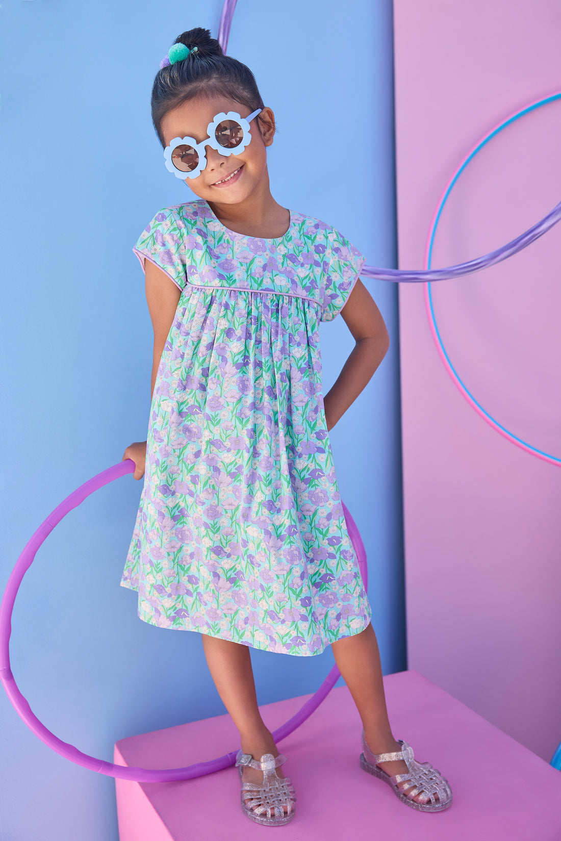 Model can be seen wearing aqua/purple/green floral print that features button closure along back neckline and a beautiful hot pink trim along bust and sleeves to elevate the look. 