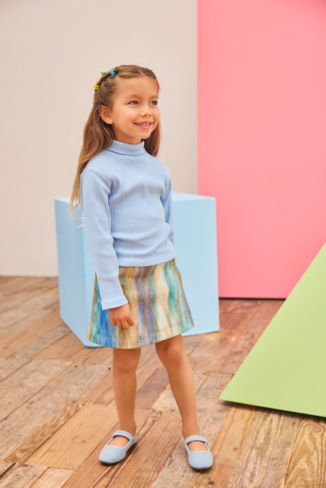 Model can be seen wearing a multi stripe wool skort in a brown/blue/aqua pattern paired back with a ribbed turtleneck in light blue to complete the look. 
