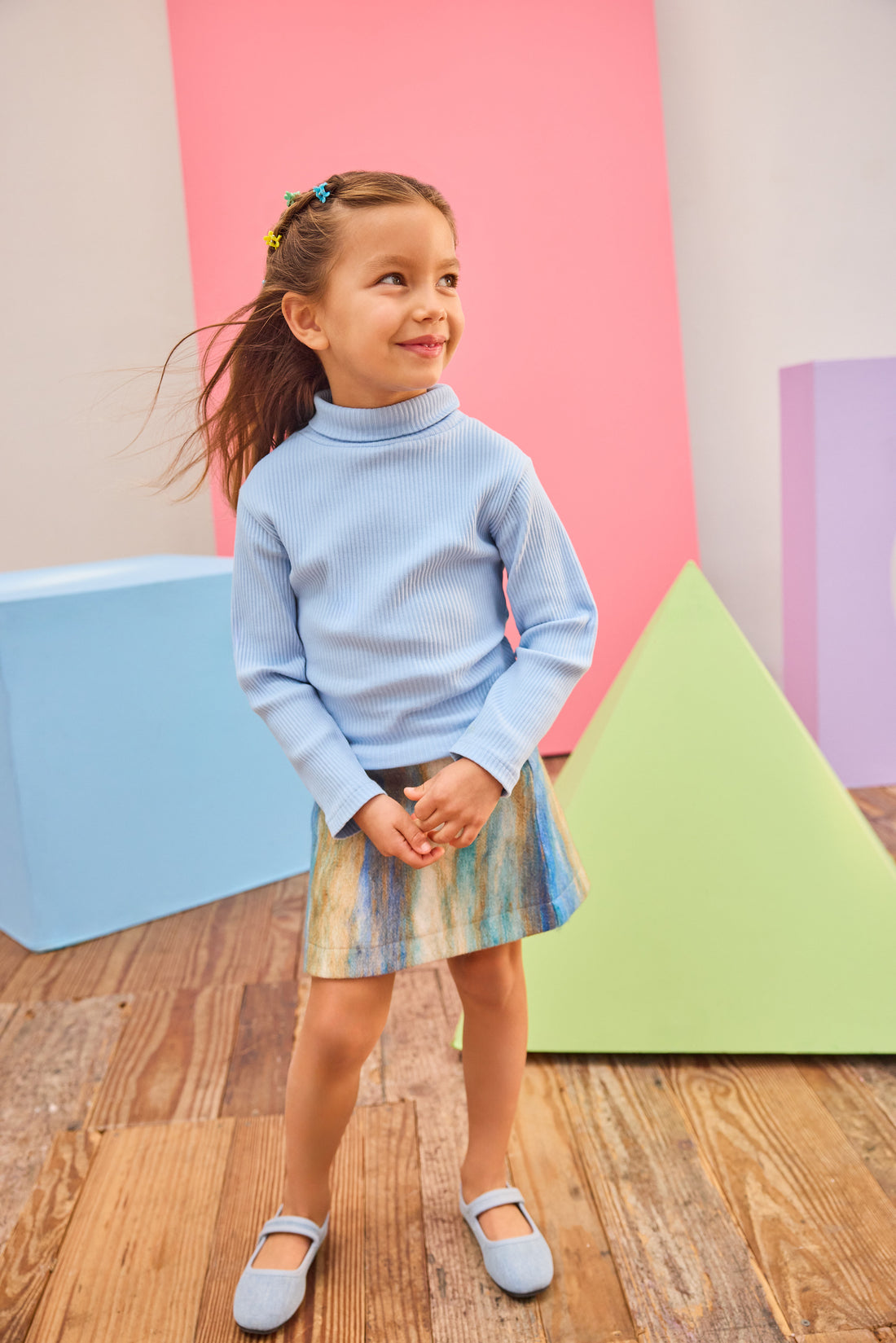 Model can be seen wearing a multi stripe wool skort in a brown/blue/aqua pattern paired back with a ribbed turtleneck in light blue to complete the look. 