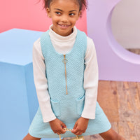 Model can be seen wearing a knit quilted jumper in an aqua color that features a gold quarter zip zipper and  two functional pockets in the front for an elevated look. Pair a ribbed turtleneck underneath to complete the look.