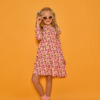 Model can be seen wearing a long sleeve knit floral dress in a fun pink/red/yellow print. Dress features ruffles at the top of the sleeves for an elevated look.