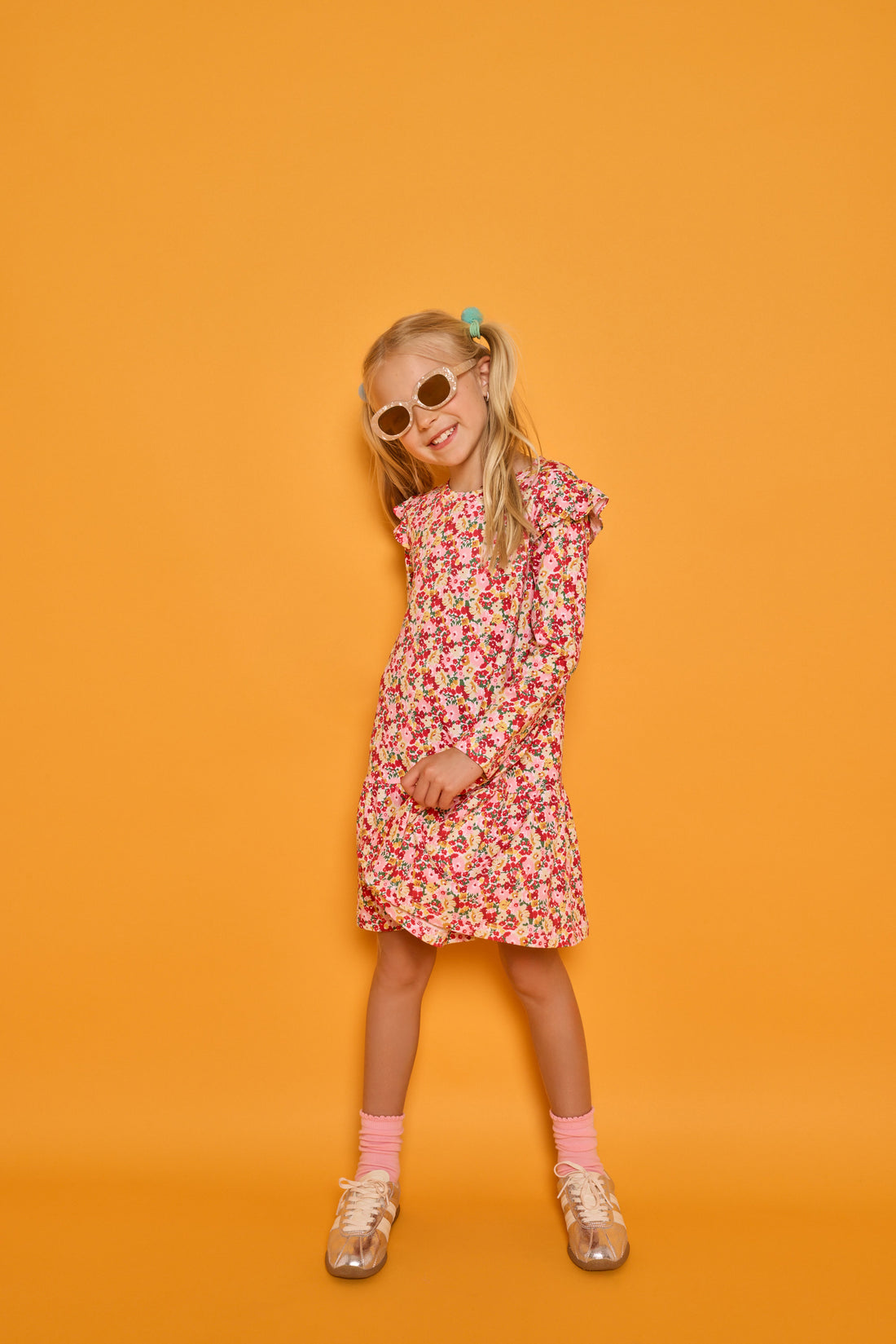Model can be seen wearing a long sleeve knit floral dress in a fun pink/red/yellow print. Dress features ruffles at the top of the sleeves for an elevated look.