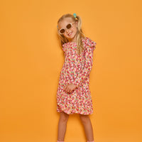 Model can be seen wearing a long sleeve knit floral dress in a fun pink/red/yellow print. Dress features ruffles at the top of the sleeves for an elevated look.