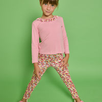 Model can be seen wearing a pink striped knit long sleeve tee with a pink/red/yellow floral ruffle detail along neckline that pairs back perfectly with the print of the knit leggings paired back with it. 