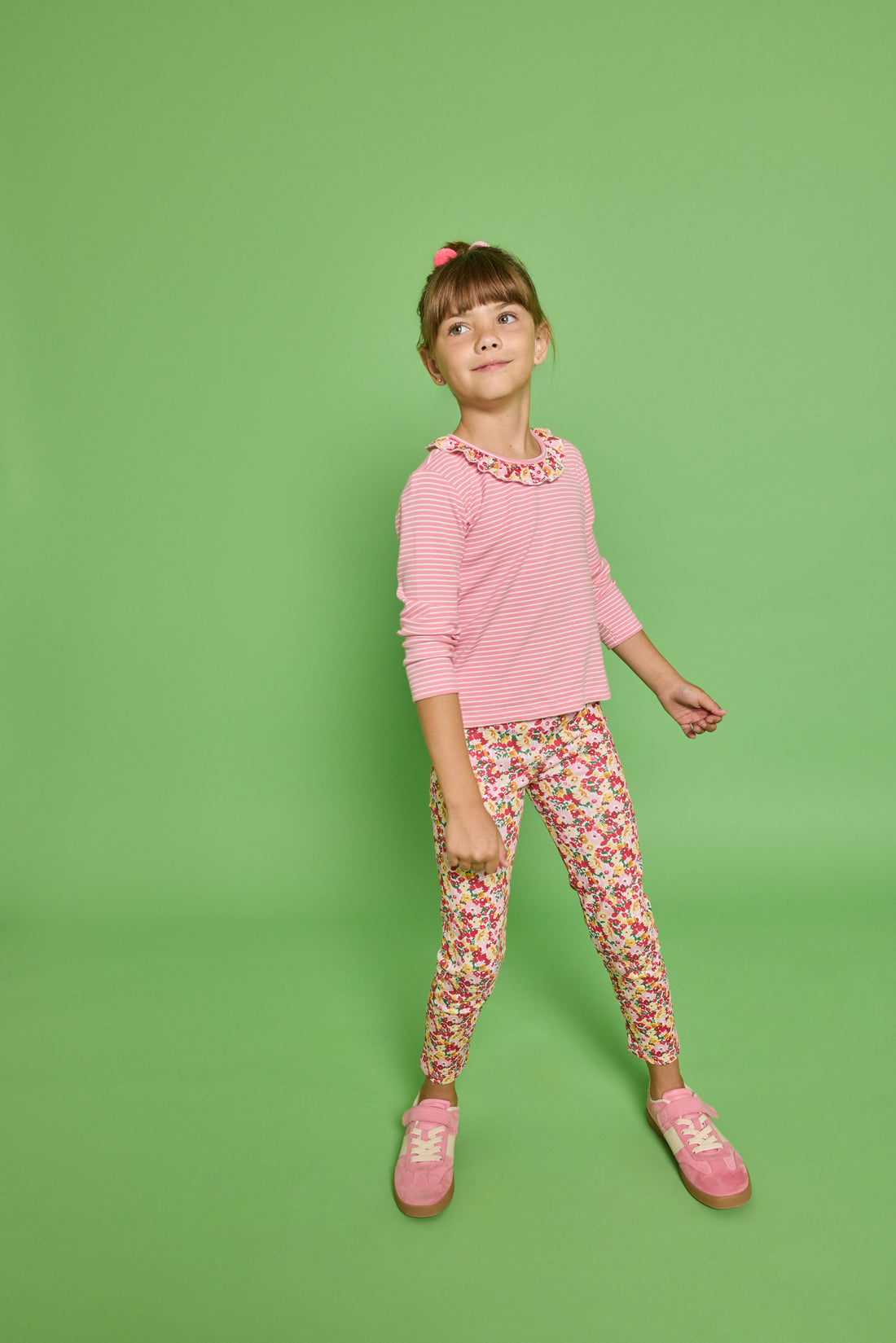 Model can be seen wearing a pink striped knit long sleeve tee with a pink/red/yellow floral ruffle detail along neckline that pairs back perfectly with the print of the knit leggings paired back with it. 