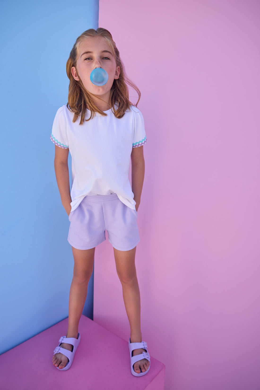 Model can be seen wearing a white knit tee that has a aqua/lavender ric rac detail at cuffs of sleeves. Shirt pairs back perfectly with knit lavender shorts to complete the look. 