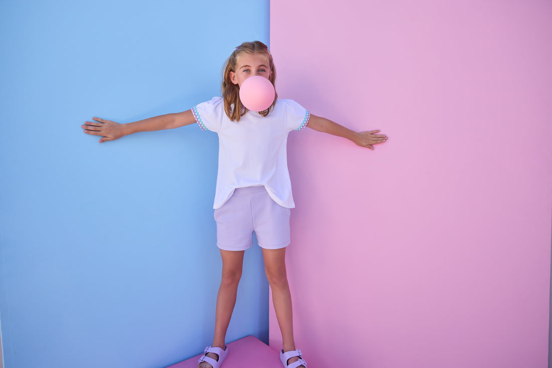 Model can be seen wearing a white knit tee that has a aqua/lavender ric rac detail at cuffs of sleeves. Shirt pairs back perfectly with knit lavender shorts to complete the look. 