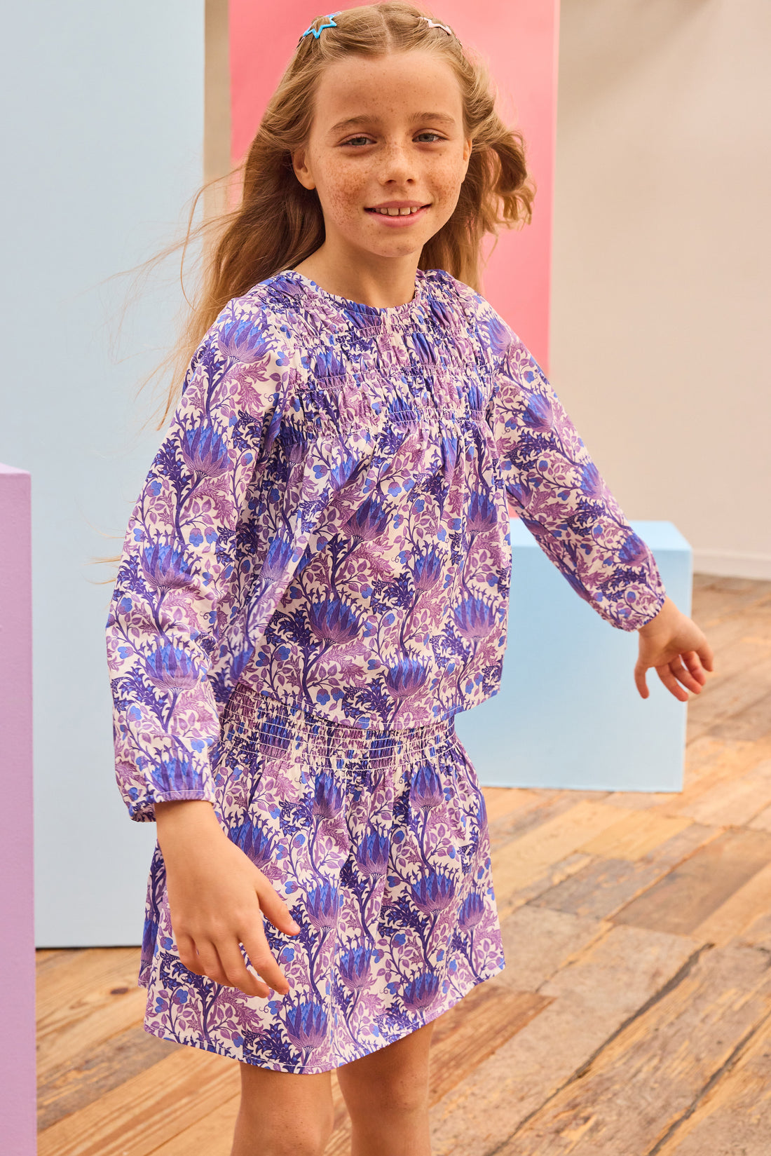 Tween model can be seen wearing purple/blue/white floral patterned top that has smocking/ruching across the bust for an elevated look which also pairs back perfectly with our skort in the same print. 