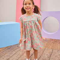 Model can be seen wearing a woven short sleeve dress in a gorgeous salmon pink/teal/green floral print that features button closures along back and green  trim detail across bust and along sleeves for an elevated look. 