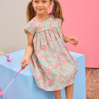 Model can be seen wearing a woven short sleeve dress in a gorgeous salmon pink/teal/green floral print that features button closures along back and green  trim detail across bust and along sleeves for an elevated look. 