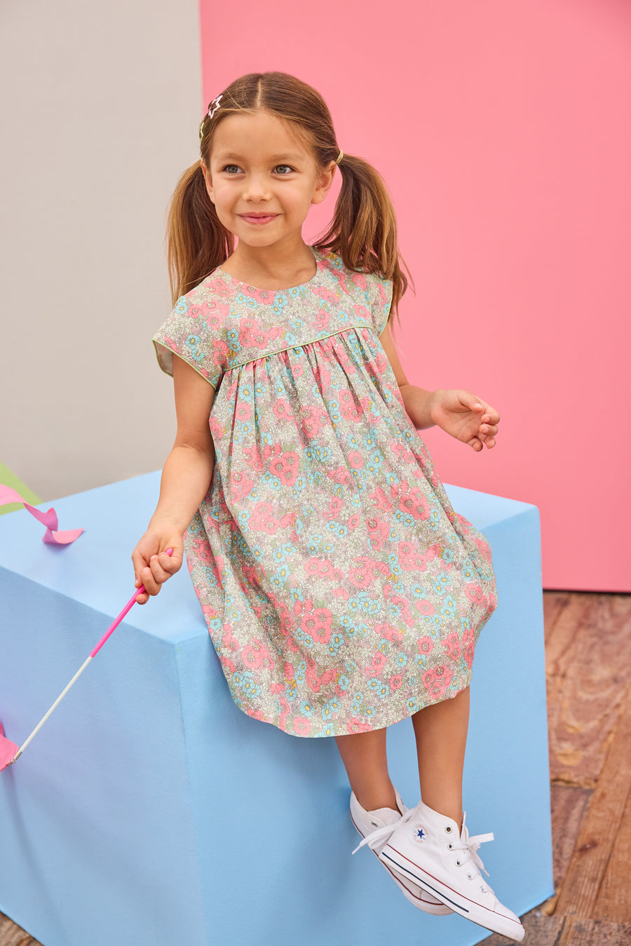 Model can be seen wearing a woven short sleeve dress in a gorgeous salmon pink/teal/green floral print that features button closures along back and green  trim detail across bust and along sleeves for an elevated look. 