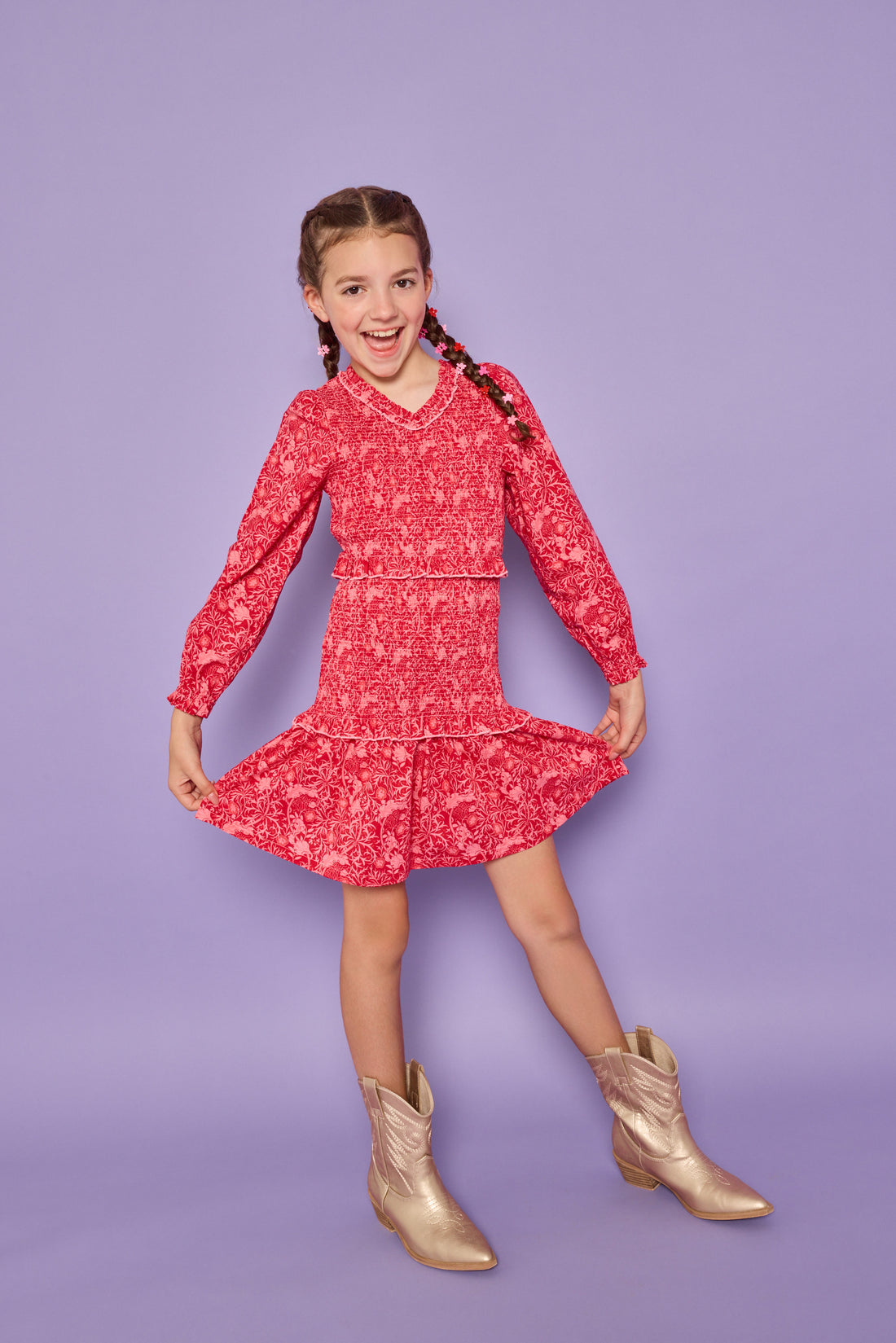 Model can be seen wearing a red/pink floral woven ruched dress. Dress features elastic ruching throughout, a v-neck neckline, and elastic cuffs at sleeves. 
