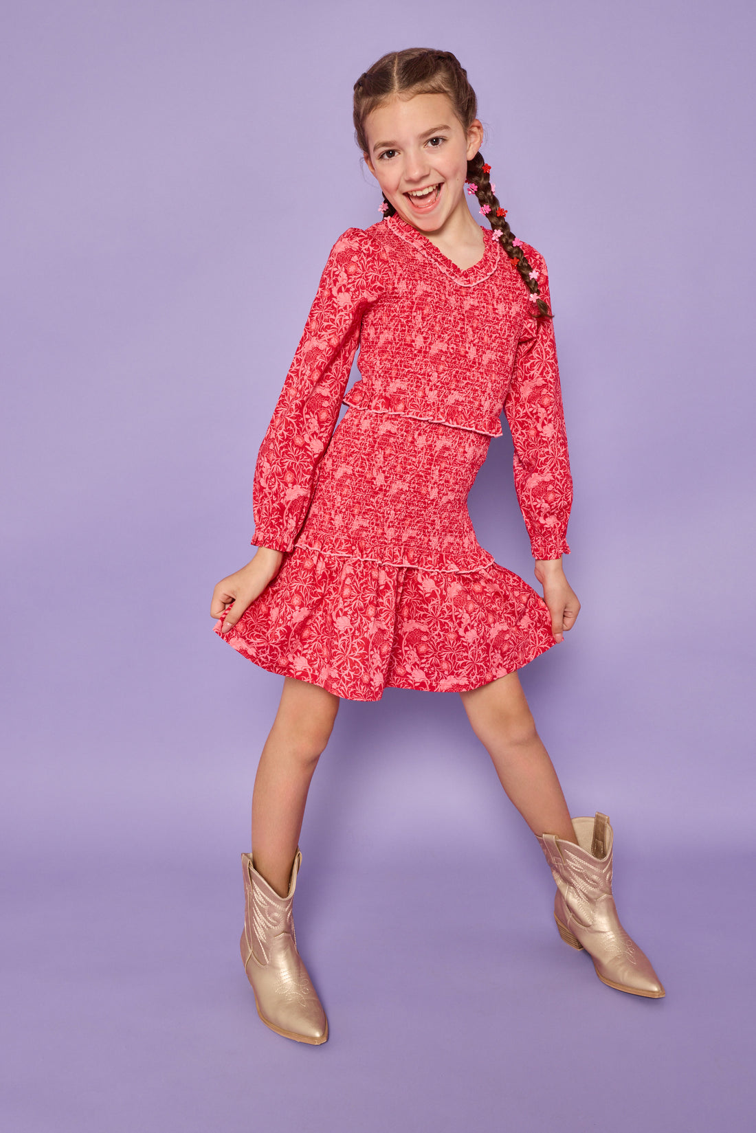 Model can be seen wearing a red/pink floral woven ruched dress. Dress features elastic ruching throughout, a v-neck neckline, and elastic cuffs at sleeves. 