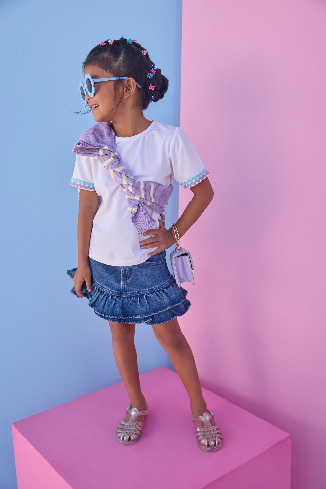 Model can be seen wearing a denim mini skirt that features ruffle detail and button closure for a secure fit. Pair skirt back with a ric rac tee to complete the look. 
