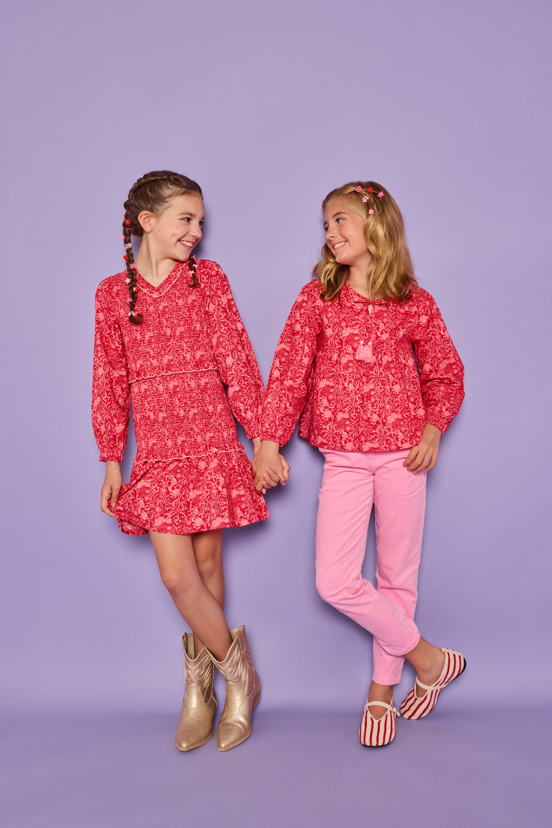 Models can be seen wearing a red and pink floral print in either a woven ruched dress on the left or a woven long sleeve top on the right. The top features tie tassels in the front of the v-neckline for an elevated look, which pairs back perfectly with our corduroy pants in the matching pink color. 