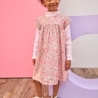 Model can be seen wearing woven short sleeve dress, with a ribbed turtleneck paired underneath to complete the look. Dress features a beautiful pink/green floral, button closure on back, and a beautiful green trim across bust and edge of sleeves for an elevated look. 