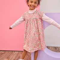 Model can be seen wearing woven short sleeve dress, with a ribbed turtleneck paired underneath to complete the look. Dress features a beautiful pink/green floral, button closure on back, and a beautiful green trim across bust and edge of sleeves for an elevated look. 
