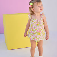 Baby model can be seen wearing a two piece woven bloomer set in a beautiful pink and yellow floral print. Top features button closure at end of straps along back, and bottoms are easy pull on style for a secure but comfy fit. 