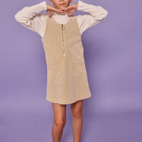 Model can be seen wearing oatmeal long sleeve ribbed knit top with paired underneath a stone corduroy jumper that features a quarter zip zipper and herringbone detail for an elevated look.
