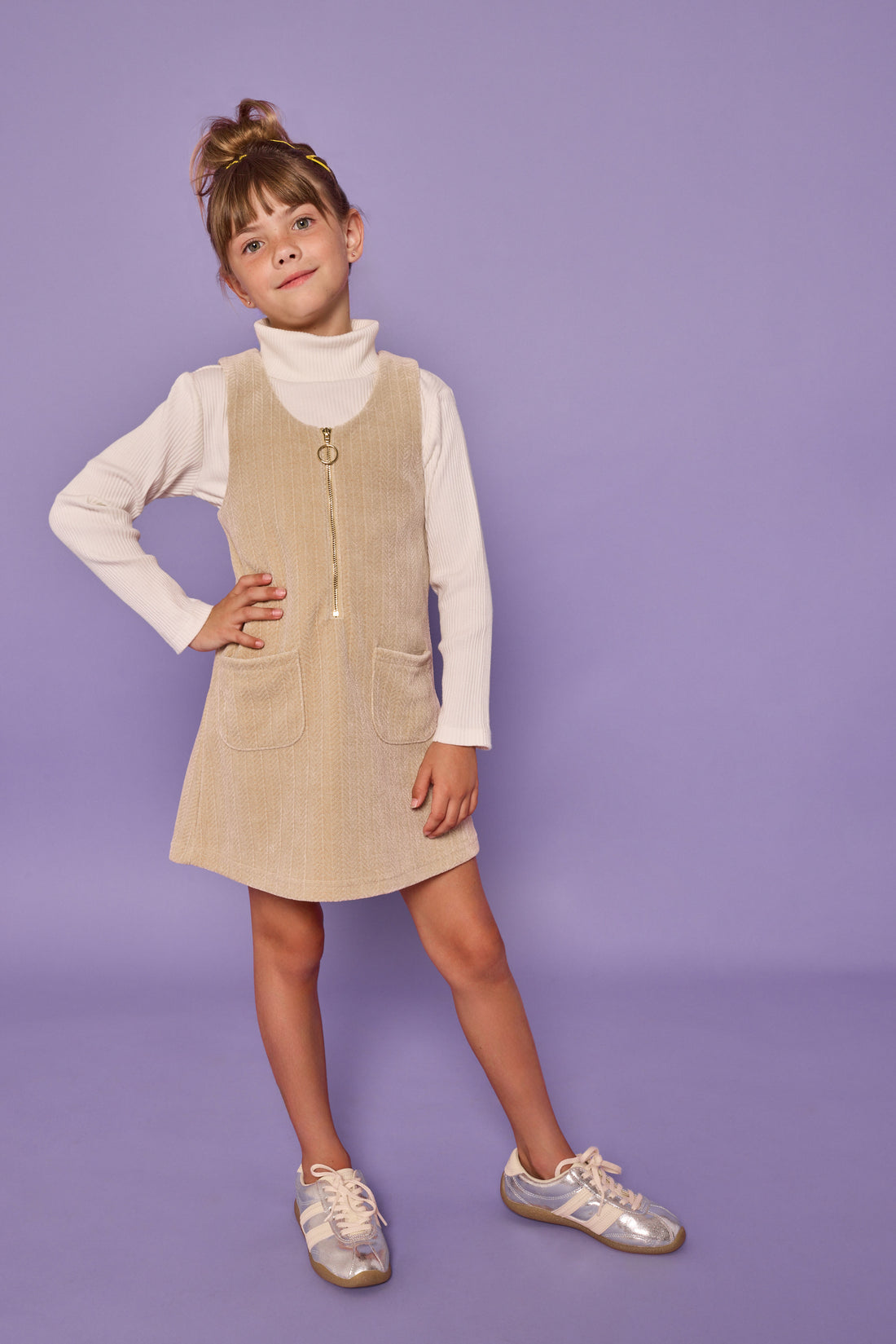 Model can be seen wearing oatmeal long sleeve ribbed knit top with paired underneath a stone corduroy jumper that features a quarter zip zipper and herringbone detail for an elevated look.