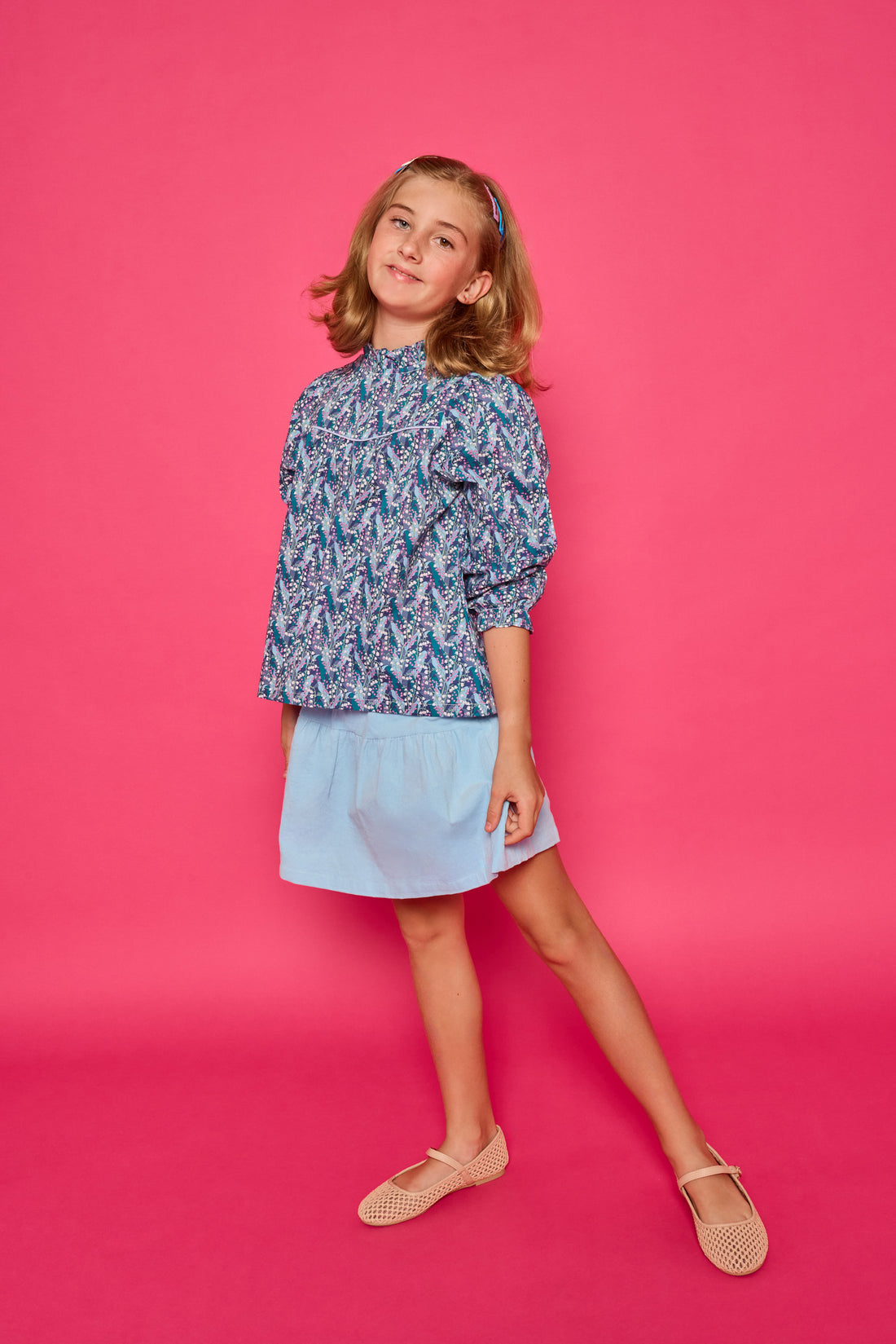 Model can be seen wearing a woven top with a ruffle neckline and button closure along back. The purple/teal/blue floral print pairs back perfectly with our skort in light blue corduroy to complete the look. 