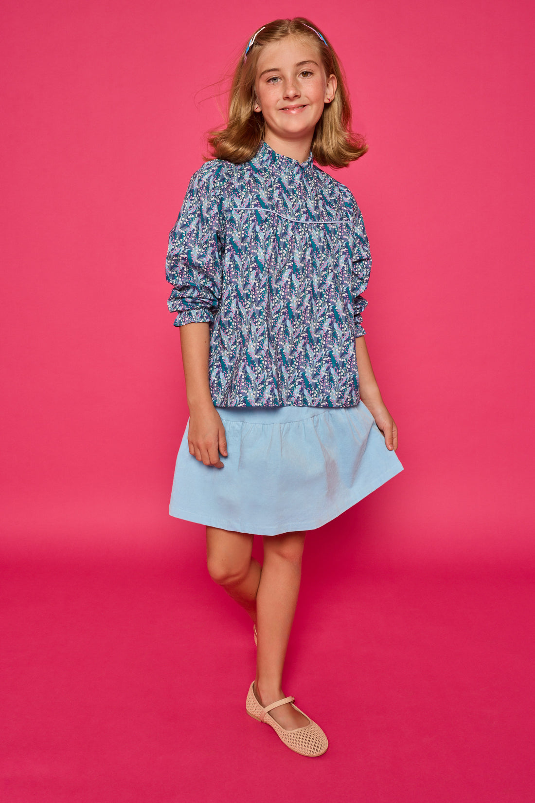 Model can be seen wearing a woven top with a ruffle neckline and button closure along back. The purple/teal/blue floral print pairs back perfectly with our skort in light blue corduroy to complete the look. 