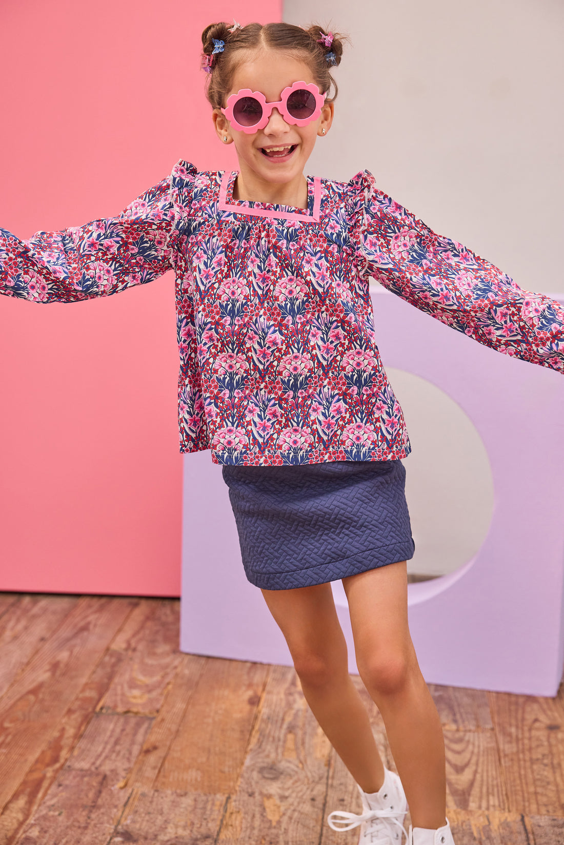 Model can be seen wearing a navy quilted knit skort that features an elastic waistband and built in shorts for a relaxed but secure fit. Skort pairs back perfectly with long sleeve woven top in navy/pink/cranberry floral print to complete the look. 