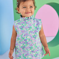 Baby model can be seen wearing a woven bloomer set in an aqua/green/purple floral print. Top of set features button closure at back and bottom features elastic waistband for easy put on/pull off access.