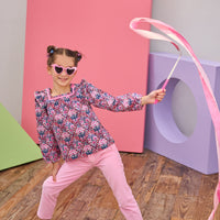 Model can be seen wearing a woven long sleeve top in a navy/pink/red floral print, paired back with bubblegum pink pants . Top features a square neckline, with a ribbon detail along neckline and slight angel sleeves to elevate the look. 