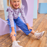 Model can be seen wearing royal blue velour pants that feature an elastic waistband and functioning pockets in the front of pants. Pants pair pack perfectly with long sleeve knit top in purple and matching blue stripe to complete the look. 