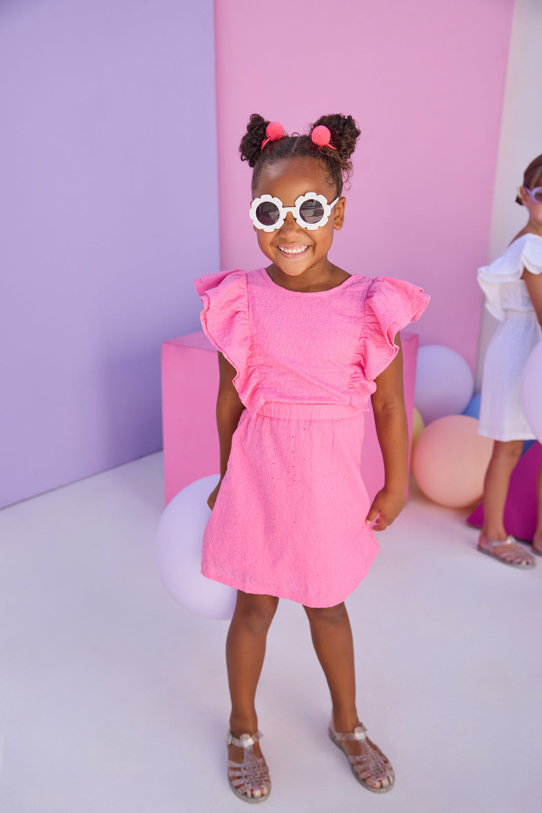 Model can be seen wearing a hot pink woven embroidery material. Dress features big angel sleeve detail and almost full open back for an elevated look. 