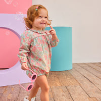 Baby girl can be seen wearing a woven bubble in a gorgeous pink/teal floral that features a ruffle neckline and snap closure for easy put on/pull off access. 