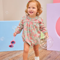 Baby girl can be seen wearing a woven bubble in a gorgeous pink/teal floral that features a ruffle neckline and snap closure for easy put on/pull off access. 
