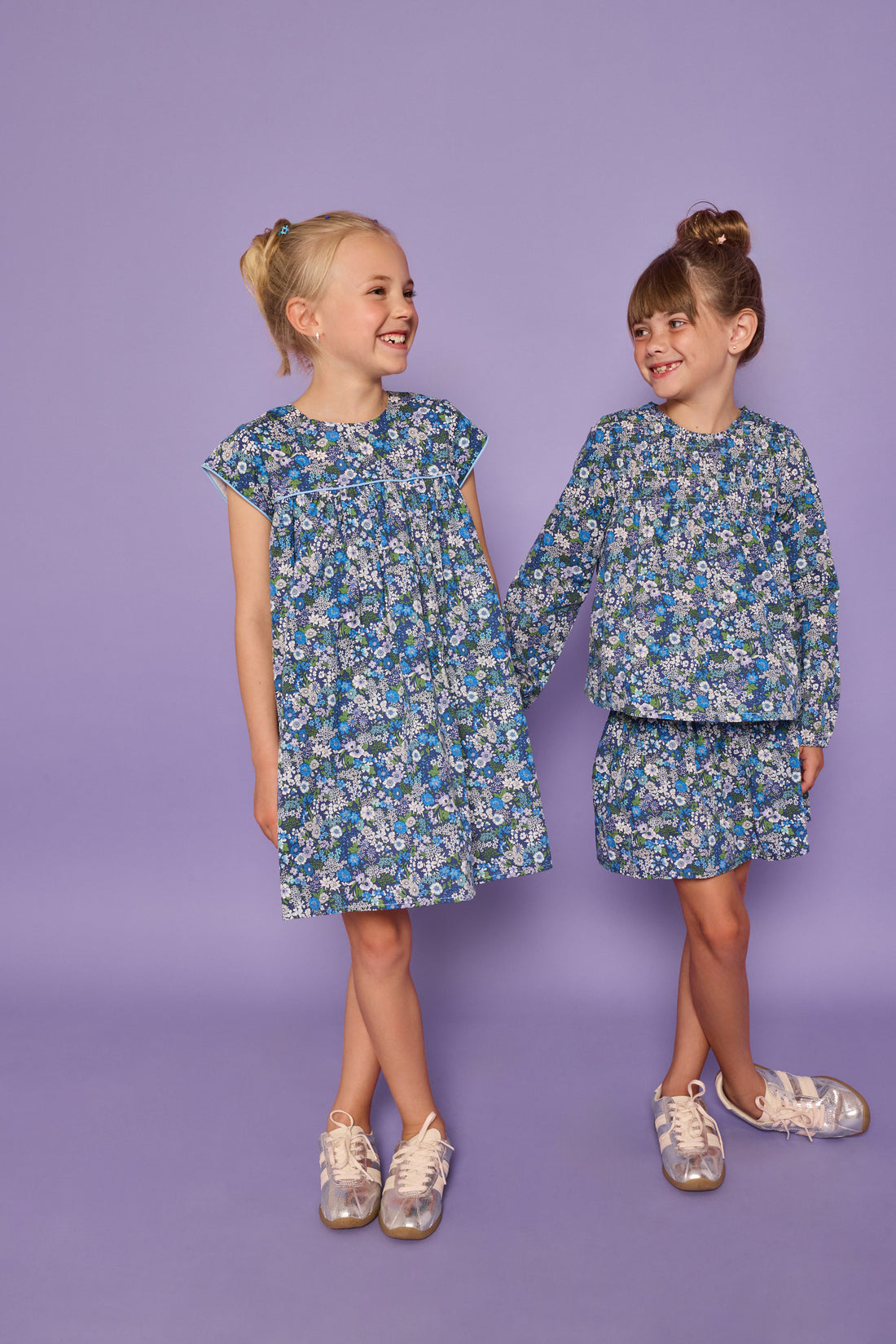 Models can be seen wearing a floral print in blue/purple/and green. Print comes in a short sleeve woven dress and in a long sleeve woven top and skirt for options for little girl. 