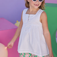 Model can be seen wearing shirred shorts in a salmon pink/green floral print. Shorts feature smocking along waist and scallop edges to elevate the look. Shorts pair back perfectly with woven white top with a square neckline for an elevated but comfy look. 