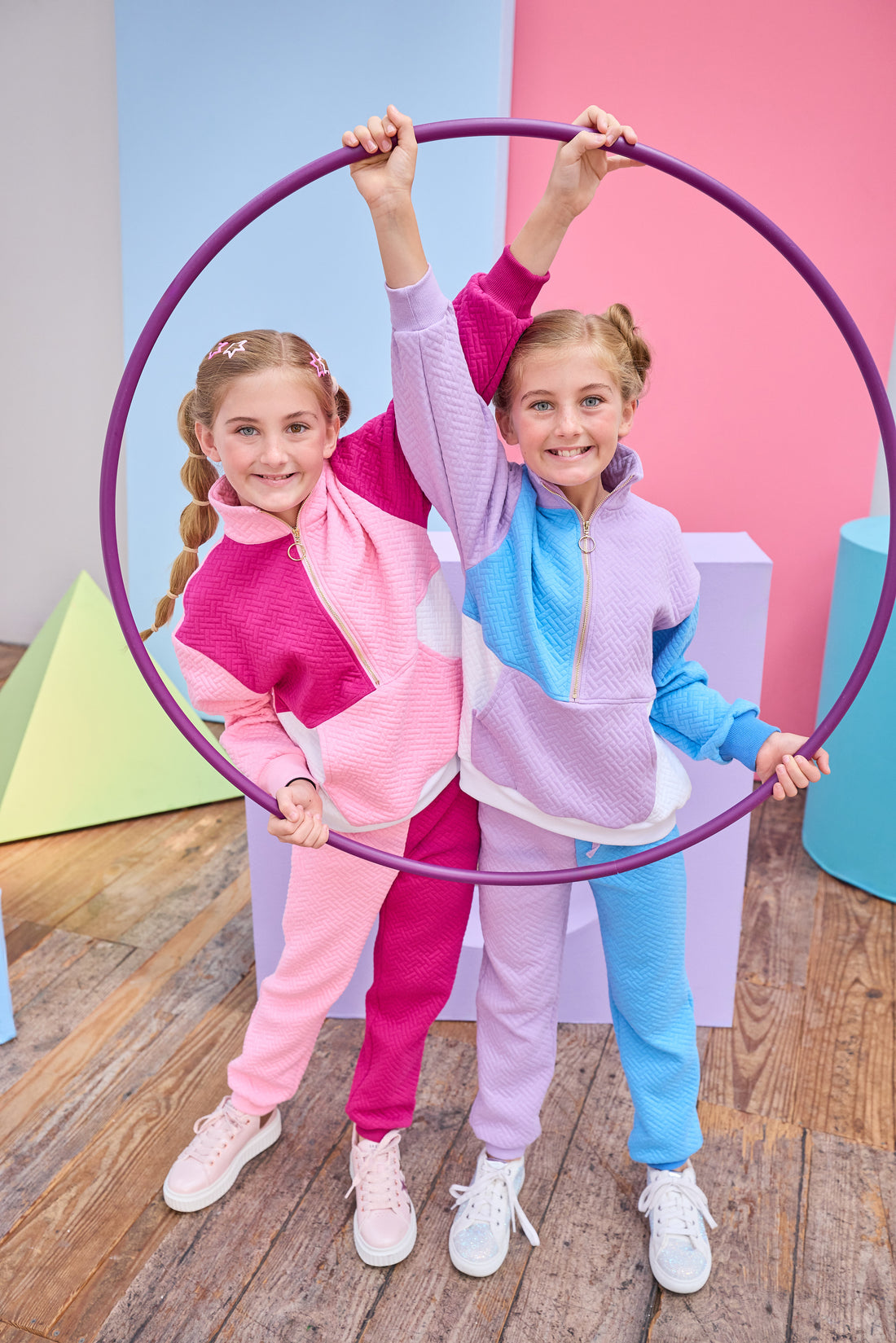 Models can be seen wearing matching color block jogger sets in lilac/aqua and cranberry/pink. Sets are made of a knit material and feature gold quarter zip detail and joggers have adjustable tie waists for a relaxed and comfy fit. 