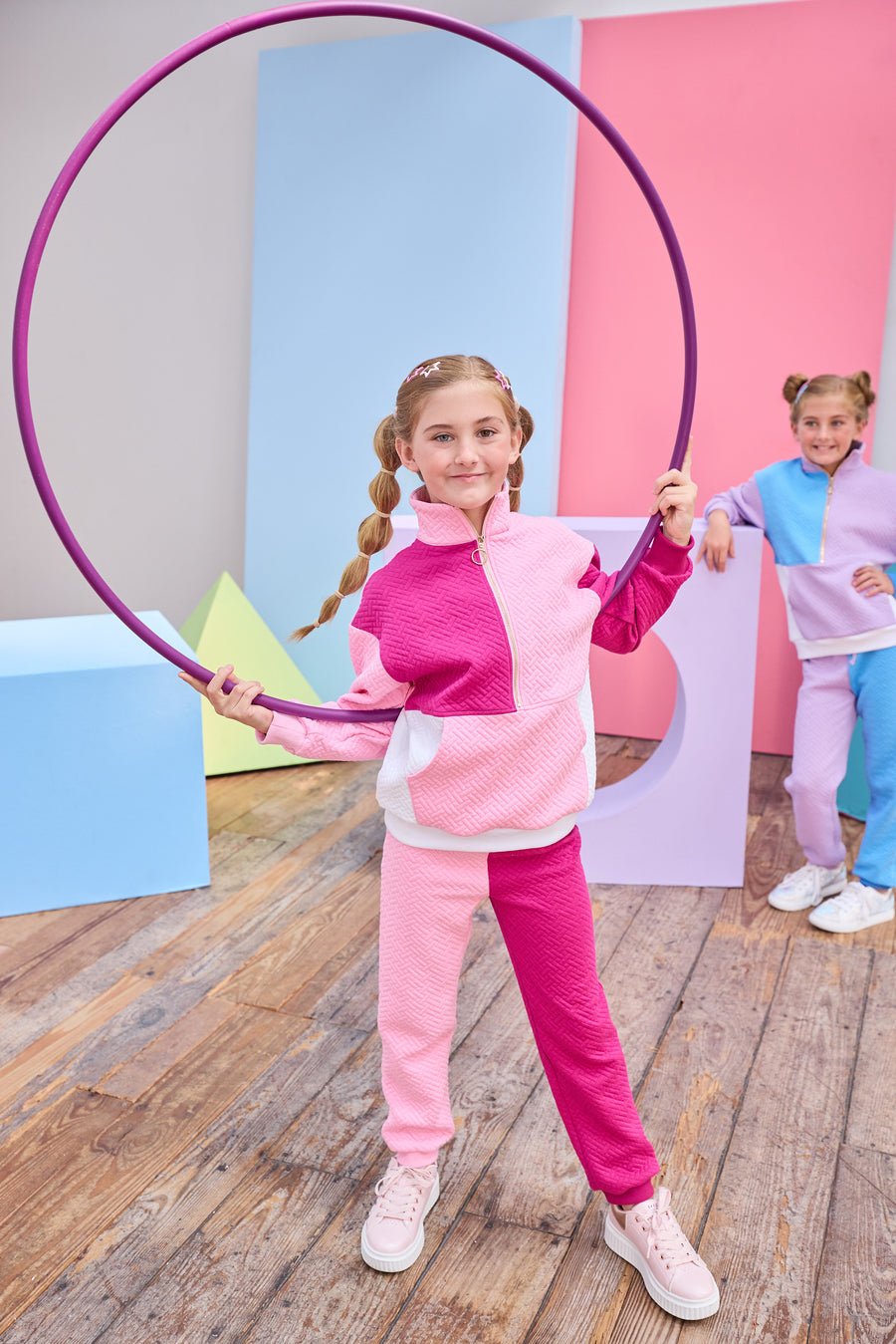 Model can be seen wearing a matching color block set in pink/cranberry/and white. Pullover features a gold quarter zip zipper detail and large front pocket for a relaxed but secure fit. Pullover matches back perfectly to the joggers, and continues with the color block with a pink pant leg and an cranberry pant leg.