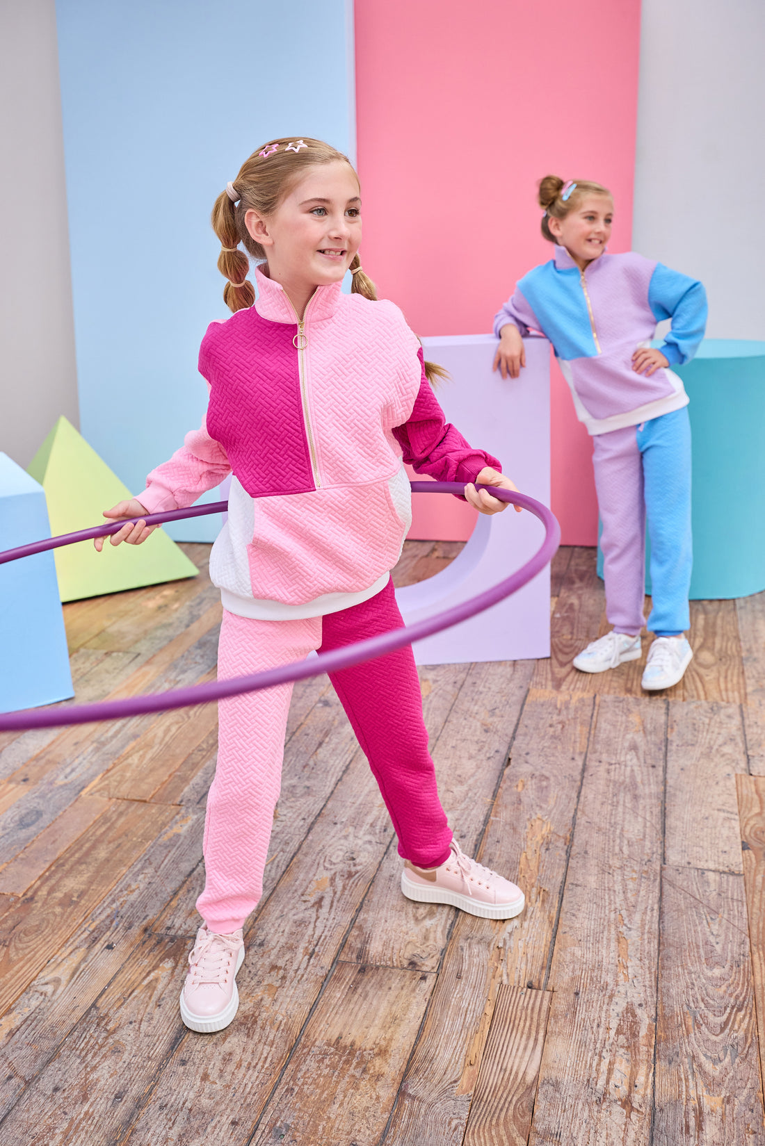 Model can be seen wearing a matching color block set in pink/cranberry/and white. Pullover features a gold quarter zip zipper detail and large front pocket for a relaxed but secure fit. Pullover matches back perfectly to the joggers, and continues with the color block with a pink pant leg and an cranberry pant leg.