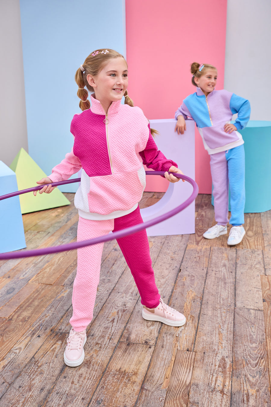 Model can be seen wearing a matching color block set in pink/cranberry/and white. Pullover features a gold quarter zip zipper detail and large front pocket for a relaxed but secure fit. Pullover matches back perfectly to the joggers, and continues with the color block with a pink pant leg and an cranberry pant leg.