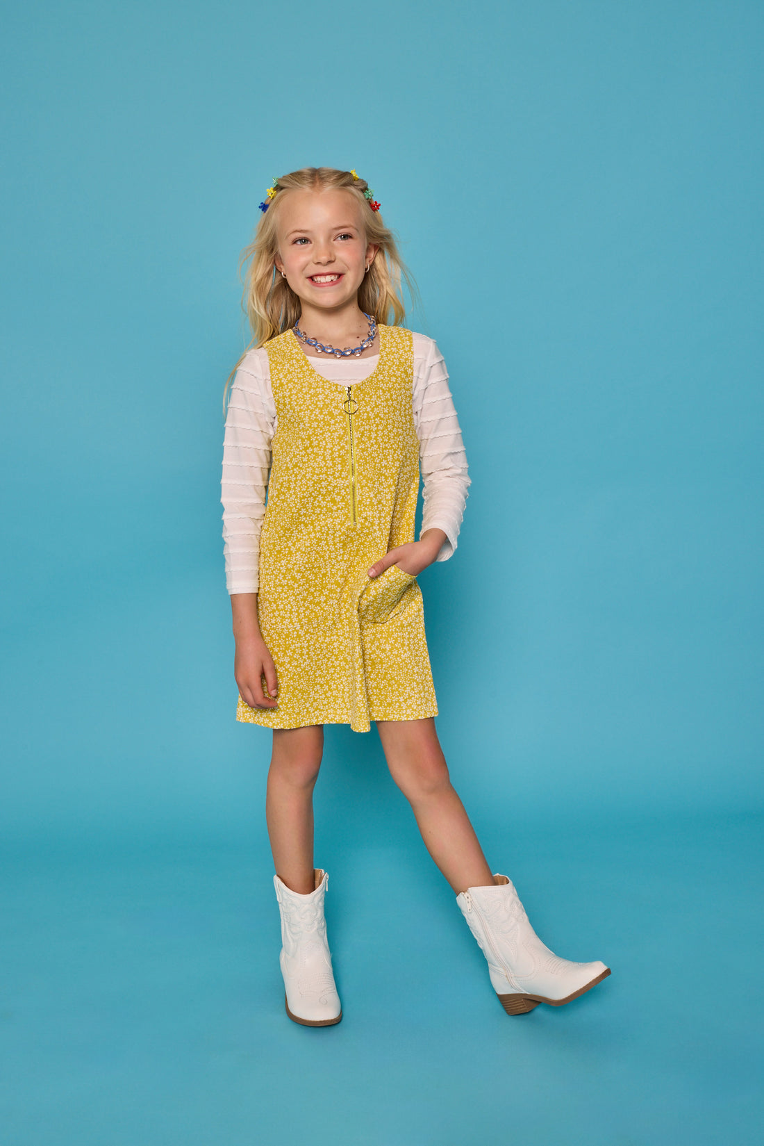 Model can be seen wearing a jumper in a yellow/white floral print. Jumper is made of a corduroy material and has a quarter zip zipper down the front. Paired nicely with our essential scallop tee to complete the look. 