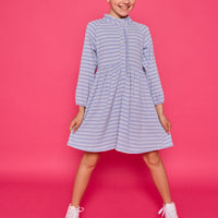 Model can be seen wearing a long sleeved knit dress in a sparkly blue and white stripe fabric. Dress features button closure down the front for a relaxed but secure fit. 