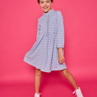 Model can be seen wearing a long sleeved knit dress in a sparkly blue and white stripe fabric. Dress features button closure down the front for a relaxed but secure fit. 