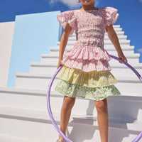 Model can be seen wearing a three tiered skort that has a pink floral top tier, yellow floral middle tier, and green floral bottom tier for an elevated look. Skort pairs back perfectly with woven top in the same pink floral as top tier to complete the look.