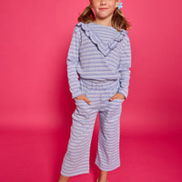Model can be seen wearing a blue/white/sparkle striped long sleeve knit shirt. Shirt features a v-ruffle detail across bust for an elevated look. 