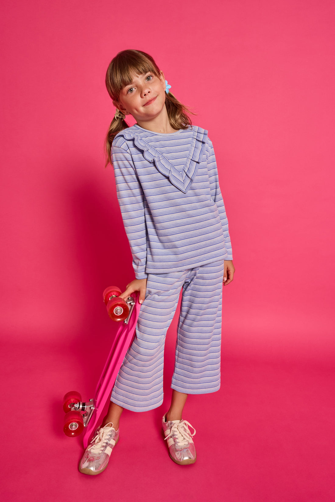 Model can be seen wearing a blue/white/sparkle striped long sleeve knit shirt. Shirt features a v-ruffle detail across bust for an elevated look. 
